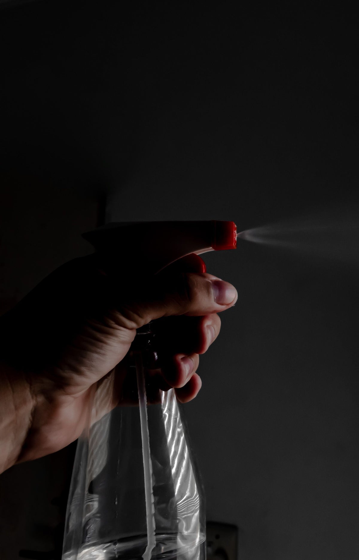 Hand spraying a fine mist from an unbranded spray bottle