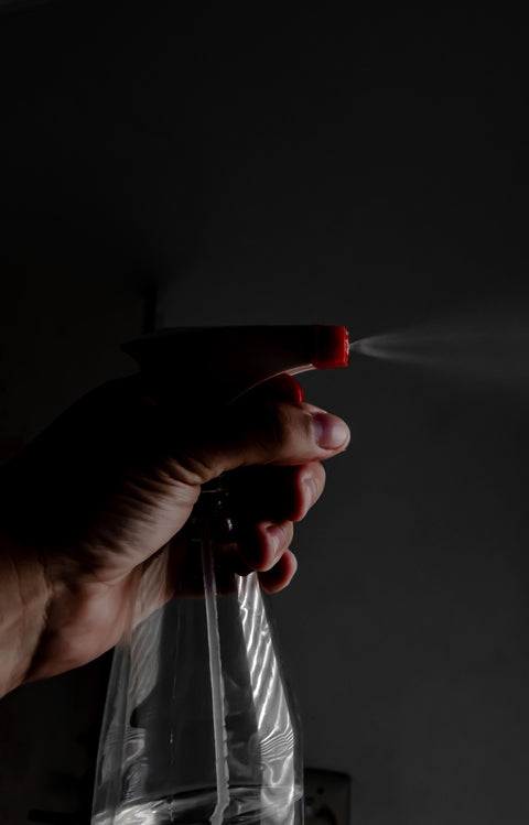 Hand spraying a fine mist from an unbranded spray bottle