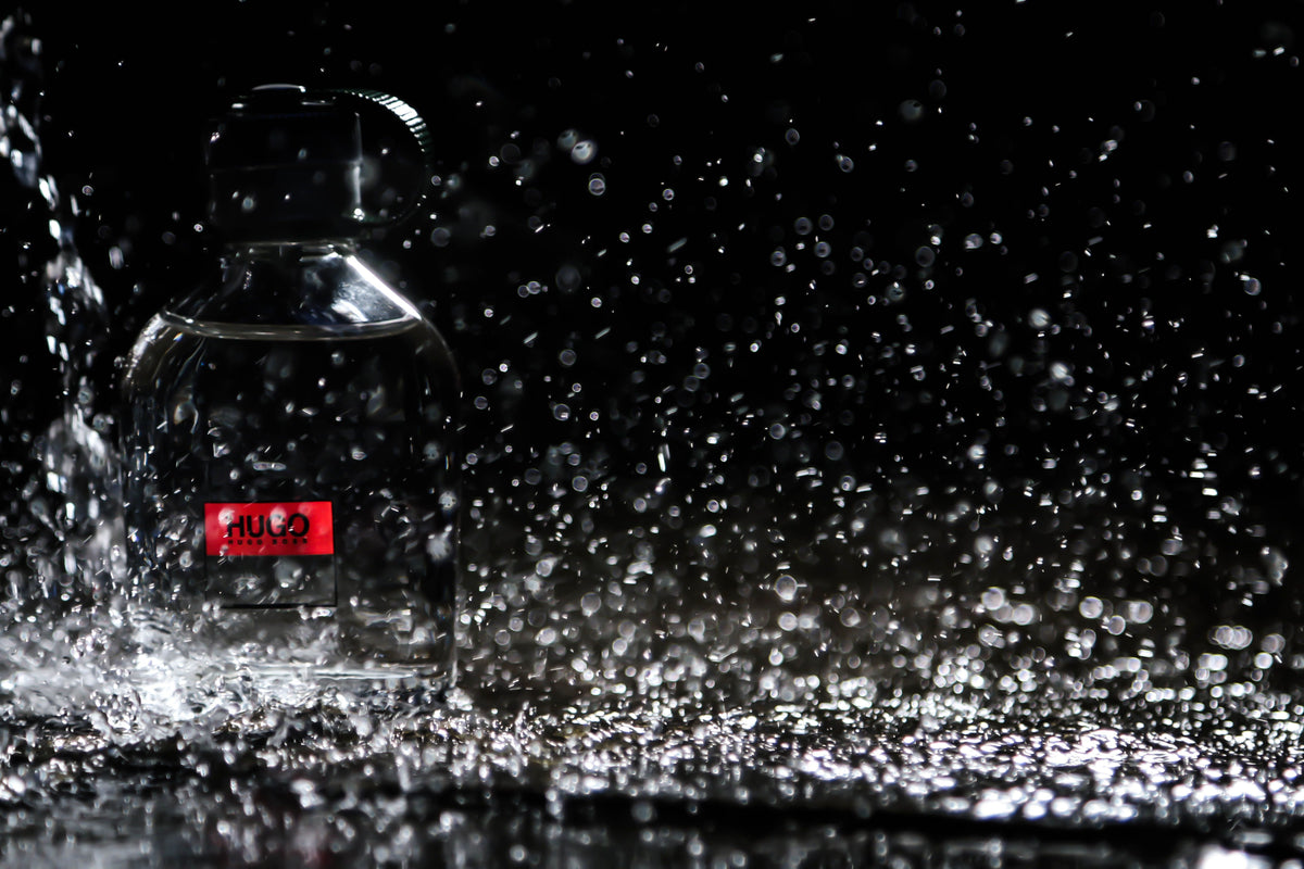 Unbranded fragrance bottle with water droplets representing scent behavior on skin