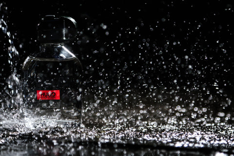 Unbranded fragrance bottle with water droplets representing scent behavior on skin