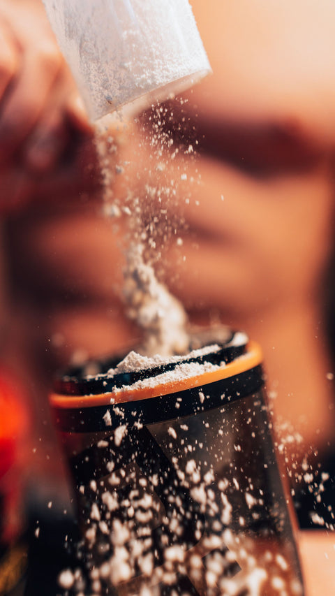 Protein powder being added to a shaker, illustrating whey protein supplements. Photo: Krzysztof Biernat / Pexels.