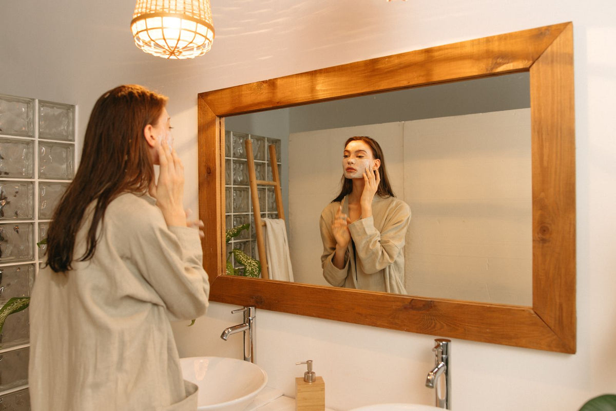 Woman applying skincare in front of a mirror