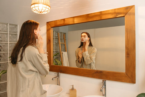 Woman applying skincare in front of a mirror