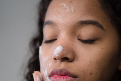 Woman gently spreading facial cleanser; illustrative cleansing photograph