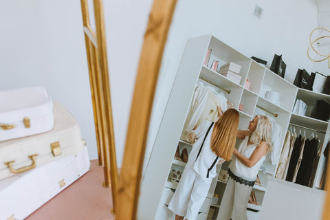 Two women choosing outfits from a stylish wardrobe