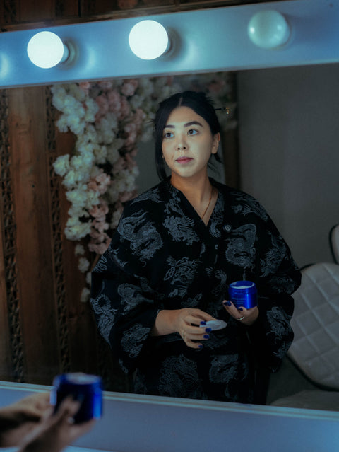 Woman doing an evening skincare routine at a vanity mirror