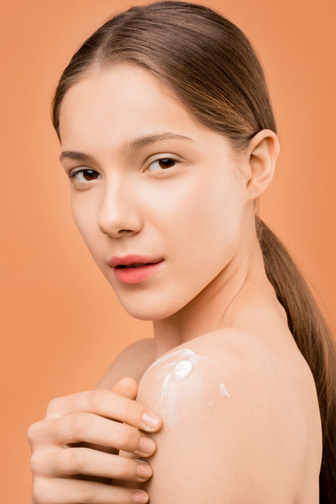 Woman applying moisturizer to dry skin on her shoulder