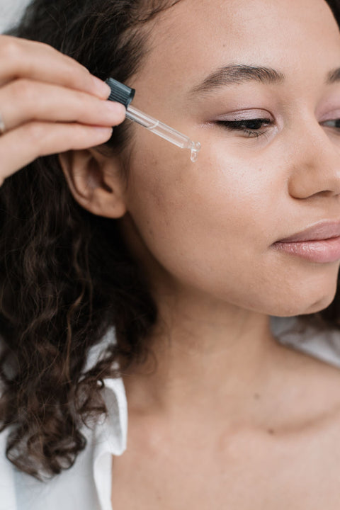 Woman applying a facial serum with a dropper during a skincare routine