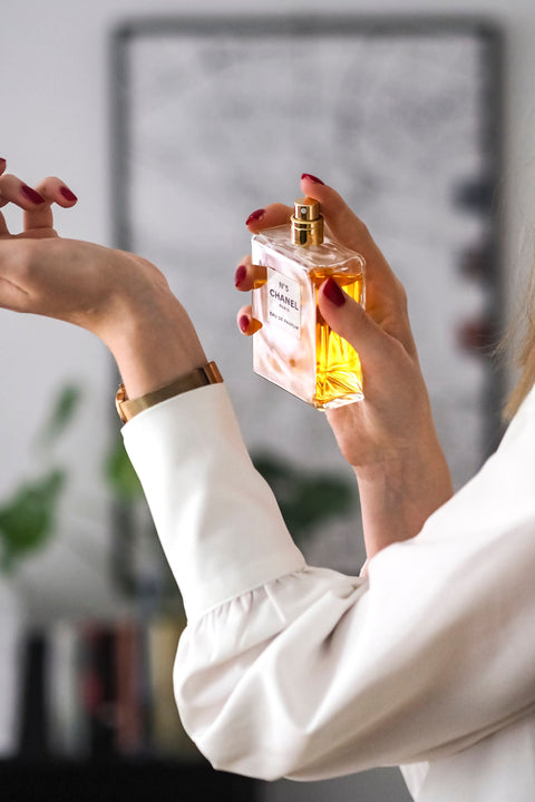 Woman applying perfume to her wrist for a fragrance layering routine