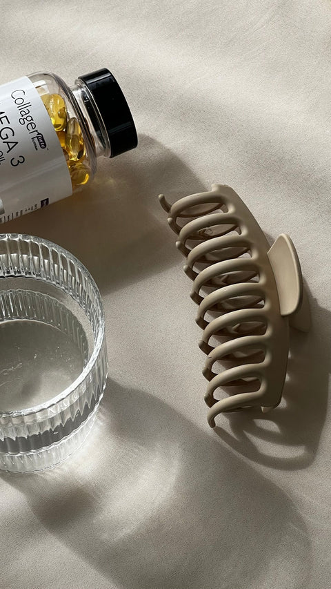 Unbranded collagen capsules beside a glass of water. Photo: Merve via Pexels.