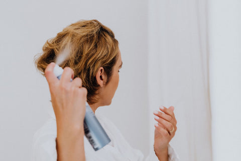 Woman spraying hair product while styling at home, Pexels