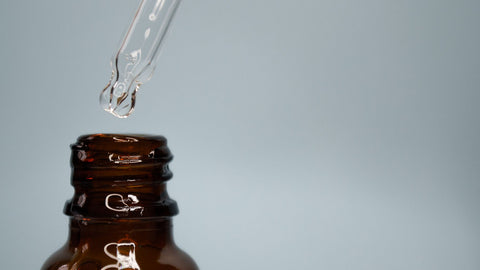 Unbranded amber glass serum bottle with pipette and clear drop, minimal scientific skincare still life. Photo via Pexels.