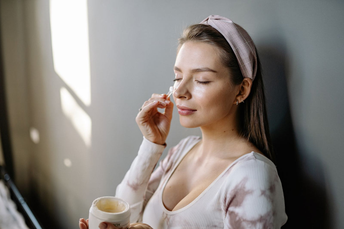 Woman applying skincare cream gently to her face, Pexels