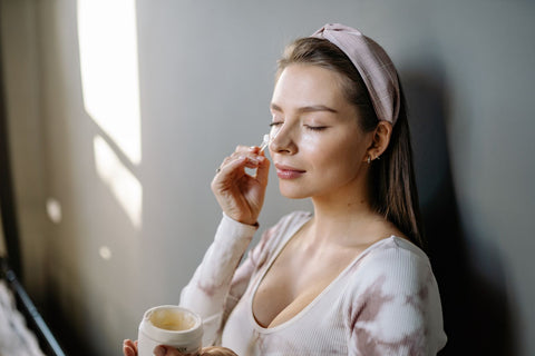 Woman applying skincare cream gently to her face, Pexels