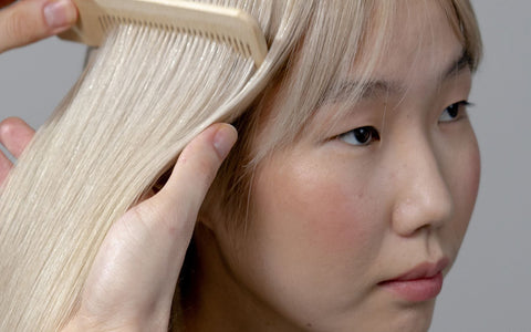 Hairstylist gently combing and parting hair in a salon for a scalp care article. Pexels: cottonbro studio.