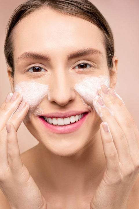 Woman washing her face with foaming cleanser, illustrating the role of surfactants in skincare.