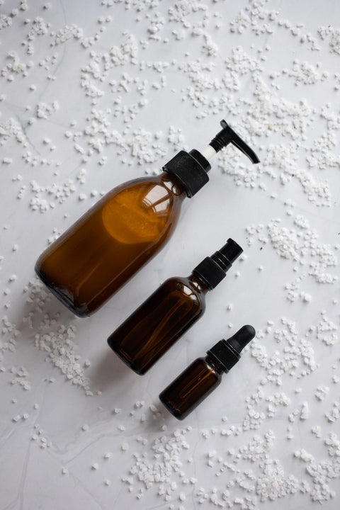 Unbranded skincare dropper and bottles in a bright setting for comparing tranexamic acid and alpha arbutin.
