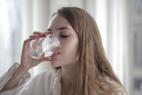 Woman drinking a clear glass of water in natural daylight, Pexels