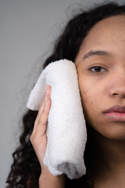 Woman gently pressing a soft towel to her face after cleansing