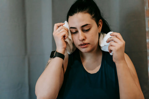Woman wiping sweat with a towel after a gym workout